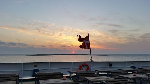 Danish flag on railing against sky during sunset