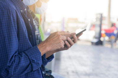 Midsection of man holding mobile phone