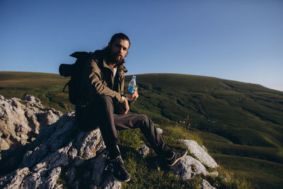 Young man on rock against sky