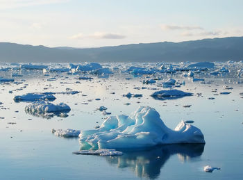 Scenic view of frozen river against sky on sunny day