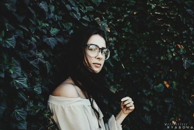 Portrait of young woman standing by tree