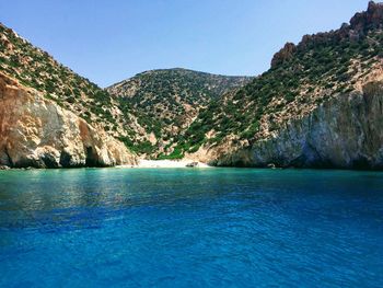 Scenic view of sea and mountains against clear blue sky