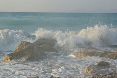 Waves splashing on shore against sky