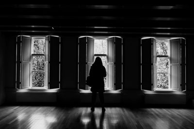 Rear view of woman standing against window