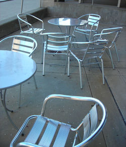 High angle view of empty chairs and table at sidewalk cafe