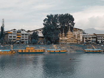 Buildings by river against sky