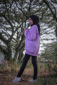 Full length of woman standing on field in forest