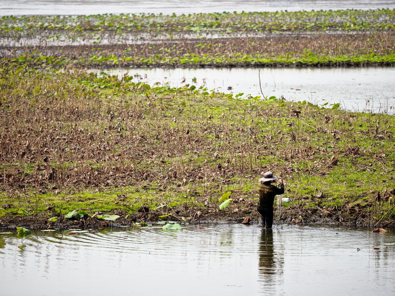 FULL LENGTH OF MAN ON LAKE BY LANDSCAPE