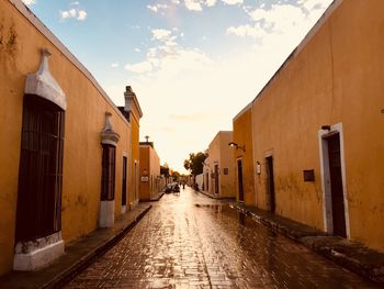 Street amidst buildings against sky during sunset