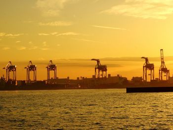 Silhouette commercial dock against sky during sunset