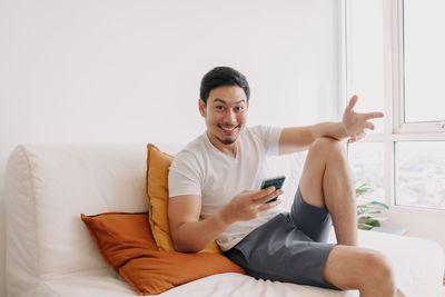 Portrait of young woman sitting on bed at home