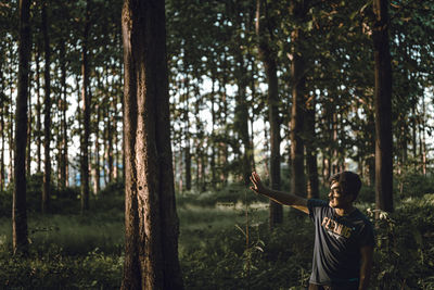 Man standing by trees in forest