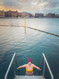 Woman by sea against sky in city