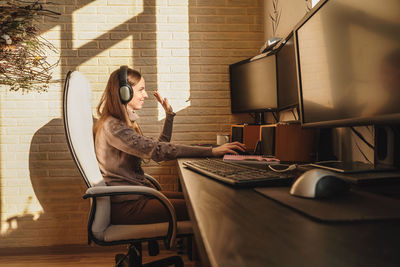 Woman gesturing while using computer on table