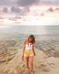 Full length of boy standing on beach against sky