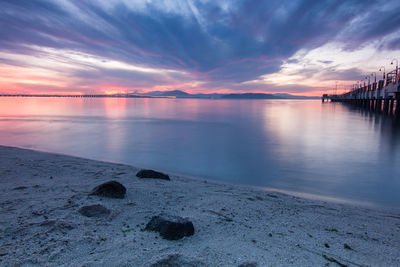 Scenic view of sea against cloudy sky at sunset