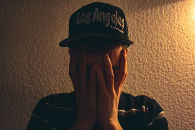 Close-up portrait of man wearing hat against wall