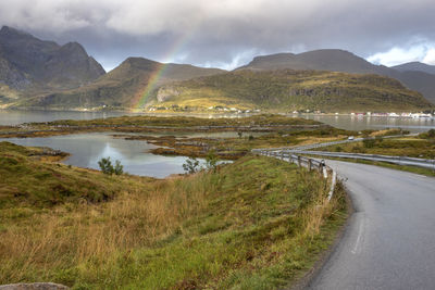 Scenic view of road by mountains against sky with the rainbow 