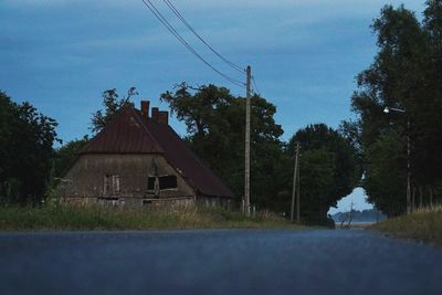 House on field by trees against sky