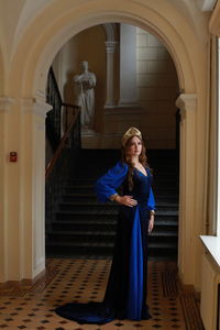 Full length portrait of teenage girl wearing royal blue dress standing at palace