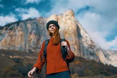 Portrait of young woman standing against mountain