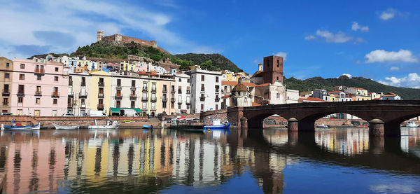 Bridge over river by buildings against sky