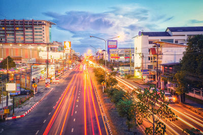 Light trails on road in city against sky