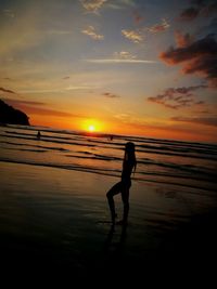 Silhouette man on beach against sky during sunset