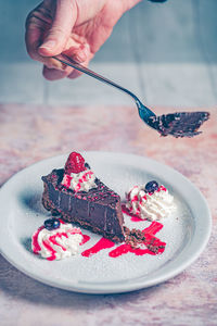 Cropped hand of person holding cake on a tea spoon 