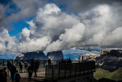 Group of people on mountain against cloudy sky