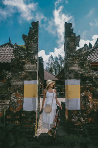 Woman holding umbrella by buildings against sky