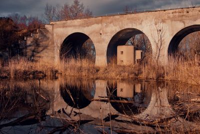 Old bridge over river against trees