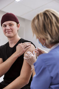 Smiling young man getting vaccinated against covid-19