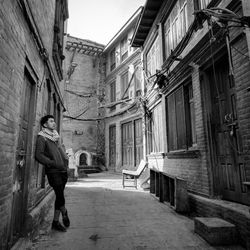 Rear view of man walking on street amidst buildings