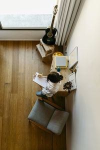 Woman writing on clipboard at home