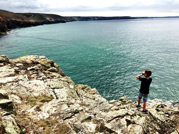 Rear view of woman photographing sea against sky