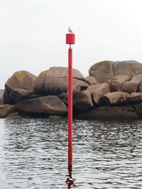 Red rock in sea against sky