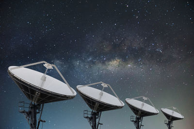 Low angle view of satellite dishes against star field