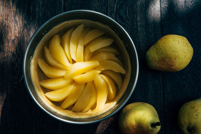 Preparation of tart with fruit slices on wooden table