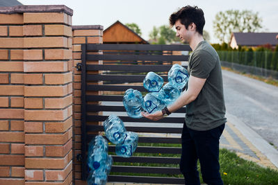 Young man throwing out empty used plastic water bottles into trash bin. collecting plastic waste