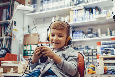 Happy kid with headphones using cb radio in a workshop.