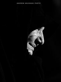 Close-up of man holding leaf over black background