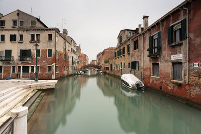 Canal amidst buildings against sky in city