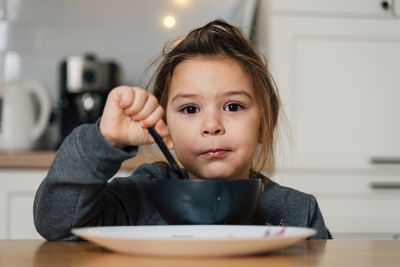 Portrait of smiling girl eating food at home