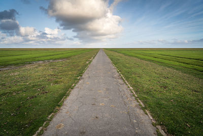 Road amidst field against sky