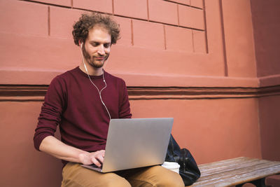 Young man using mobile phone while sitting outdoors