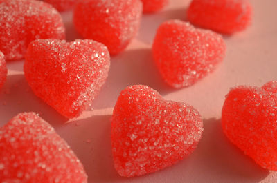 Red jelly hearts sugar coated candy on pink paper 