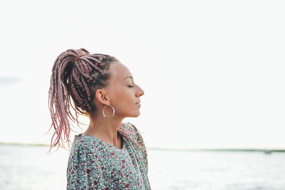 Young woman standing at beach against sky