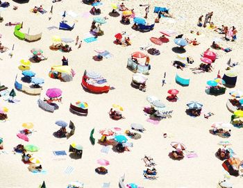 High angle view of people and parasols at beach during sunny day