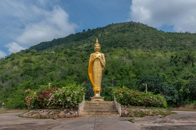 Statue against trees and plants against sky